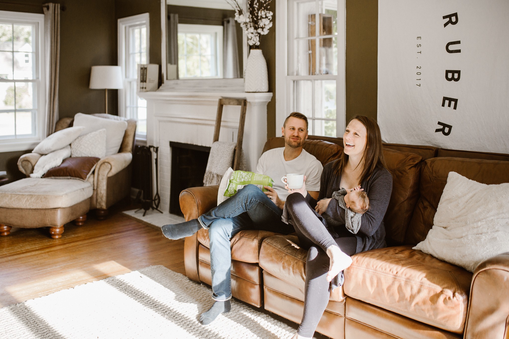 Family with a newborn baby lounging on their couch.